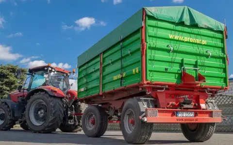 Czerwony traktor z zieloną przyczepą. Dowiedz się, jakich przyczep nie trzeba rejestrować, by ułatwić sobie pracę w gospodarstwie.