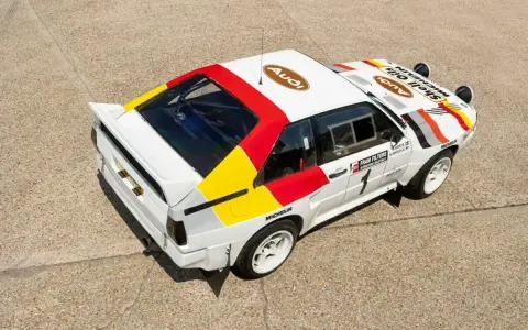 Biały rajdowy **Audi quattro S1** z kolorowymi pasami i logotypami sponsorów, gotowy do podboju szutrowych tras.