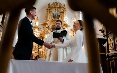 Para młoda ściska dłoń księdza podczas ceremonii. Zastanawiasz się, ile trwają nauki przedmałżeńskie?