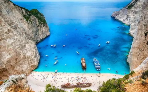 Zatoka Navagio, najcieplejsza wyspa grecka, z turkusową wodą, białym piaskiem, statkami i wrakiem.