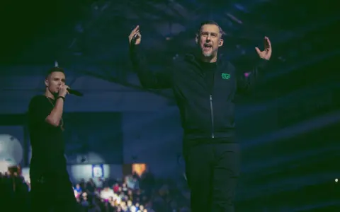 Sokół i Ero na scenie, energia tłumu, a w tle hasło "pieniądze nie śmierdzą".