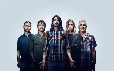 Les membres de Foo Fighters posent ensemble, cinq hommes aux regards intenses, prêts à enflammer la scène.