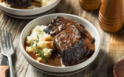 Un succulento brasato di manzo servito con purè di patate e guarnito con timo fresco.