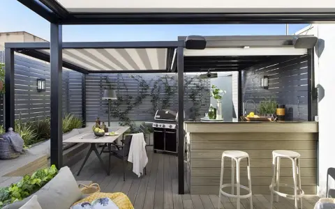 Porche moderno con mesa, parrilla y una barra de bar, ideal para disfrutar de una cocina exterior.