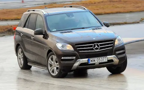 Brązowy Mercedes-Benz ML na mokrej nawierzchni, z widoczną tablicą rejestracyjną WW 0537T.