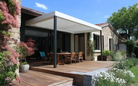 Une belle terrasse tropezienne en bois avec mobilier de jardin sous une pergola moderne. Le soleil brille sur la végétation luxuriante.
