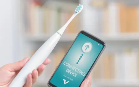 Ręka trzyma białą szczoteczkę elektryczną i smartfon z napisem "CONNECTING DEVICE". Czy mogę wziac szczoteczke elektryczna do samolotu?
