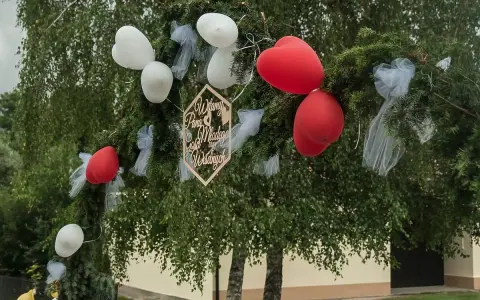 Brama weselna z balonami i napisem "Witamy Parę Młodą". Tradycja bram weselnych to symboliczne powitanie nowożeńców przez gości.