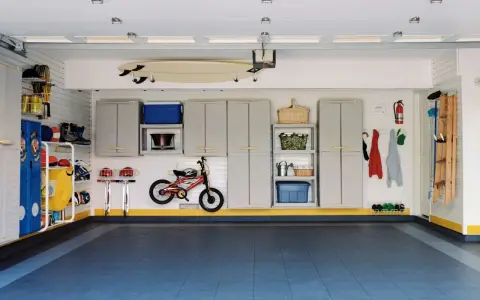 Tania podłoga w garażu, niebieska, z rowerkiem, deską surfingową i szafkami.