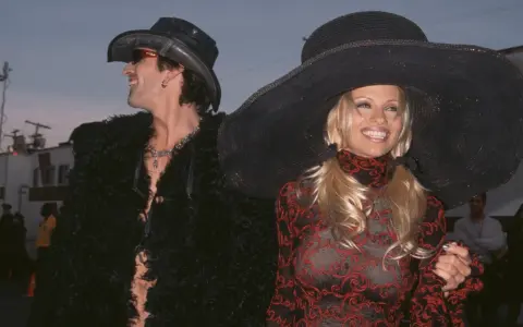 Pamela Anderson i Tommy Lee w stylizacjach z epoki. Ona w wielkim kapeluszu i wzorzystej sukience, on w kowbojskim kapeluszu i futrzanej kurtce.