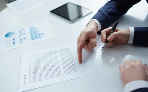 Biznesmen wskazuje palcem na dokument "CONTRACT", przygotowując się do podpisania umowy b2b.