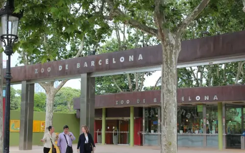 Eingang zum Zoo de Barcelona mit drei Frauen, die davor spazieren gehen.