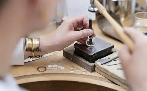 Un orfèvre au travail, façonnant une bague avec précision. Son métier d'orfèvre demande patience et dextérité.