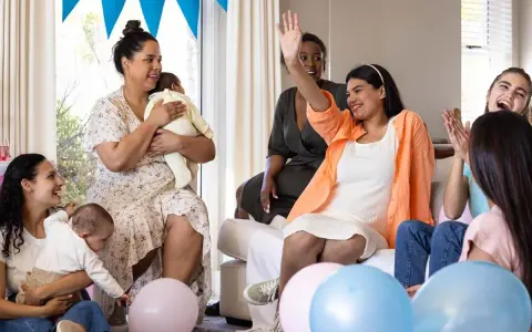 Glada kvinnor firar en babyshower med ballonger och bebisar. En kvinna vinkar glatt.