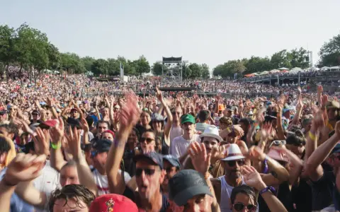 Foule en délire à un concert, mains levées. Certains portent un bouchon oreille sifflement pour se protéger du bruit assourdissant.