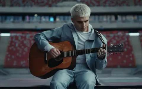 Mata gra na gitarze w pustym stadionie, zapowiadając swój nowy album.