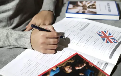 Osoba pisze ćwiczenia z angielskiego, przygotowując się do egzaminu certyfikat C2 angielski.