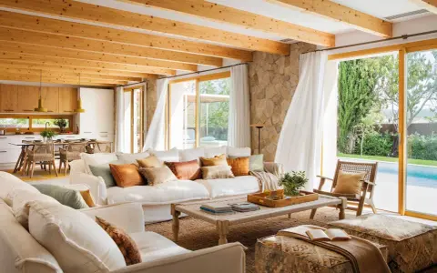 Salones de casas modernas con techos de madera, sofás blancos y vistas a una piscina.