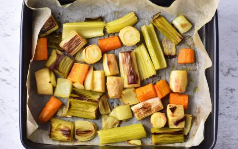 Pokrojone w kawałki marchewki, por i seler przygotowane do pieczenia. Idealne do aromatycznego rosół z pieczonych warzyw.