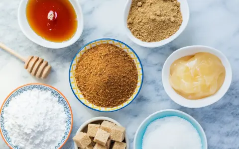 Verschiedene Süßungsmittel: Honig, brauner Zucker, Puderzucker und Würfelzucker. Hier finden Sie Alternativen, wenn Sie braunen Zucker ersetzen möchten.