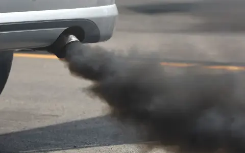 El tubo de escape de un coche emite una densa nube de humo negro al acelerar, contaminando el aire.