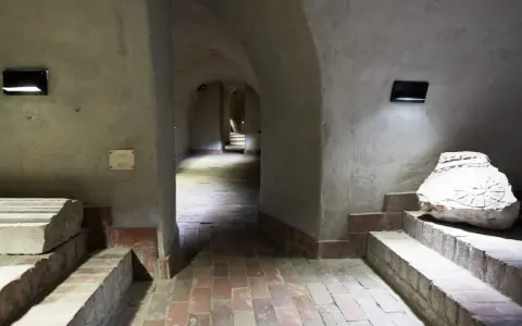 Kamienne korytarze i łuki tworzą tajemniczą trasę podziemną w Lublinie. Widać fragmenty dawnych budowli i artefakty.