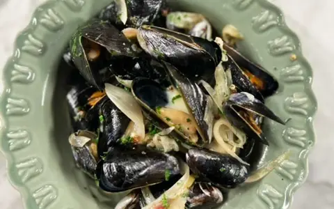 En skål med ångade musslor med lök och persilja. Ett enkelt och gott musslor recept.
