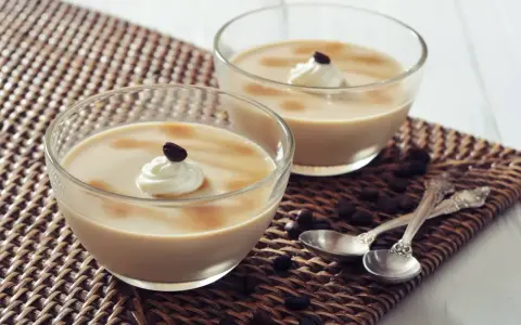 Deux verrines de crème au café façon Danette, garnies de chantilly et d'un grain de café.