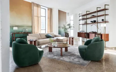 Salon au style mid century avec canapé beige, fauteuils verts velours, table basse ronde en bois et étagères murales.
