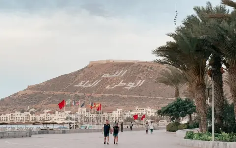 Spacerem po promenadzie w Agadirze, z widokiem na miasto i napisem na wzgórzu. Czy Agadir jest bezpieczny? Tak, wygląda na spokojne miejsce.