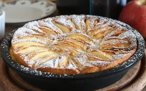 Torta di mele in friggitrice ad aria, dorata e cosparsa di zucchero a velo, pronta per essere gustata.