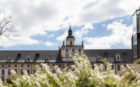 Majestatyczny gmach, idealne miejsce na studia we Wrocławiu. Wiosna kwitnie, a chmury na niebie zapraszają do nauki.