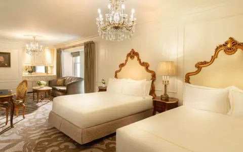 Luksusowy pokój z dwoma łóżkami w hotelu Plaza w Nowym Jorku, z kryształowym żyrandolem i złotymi zdobieniami. Zastanawiasz się, ile kosztuje noc w hotelu Plaza w Nowym Jorku?