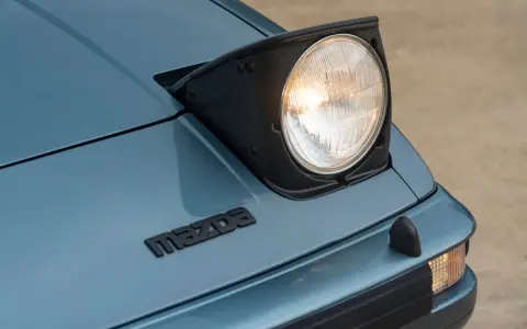Mazda RX-7 z silnikiem Wankla. Charakterystyczny, wysuwany reflektor i logo marki na niebieskim lakierze.