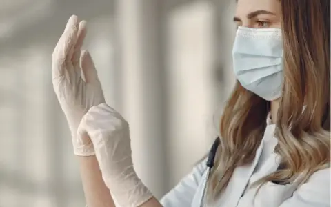 Lekarka zakłada jednorazowe rękawiczki, przygotowując się do pracy. Różne rodzaje rękawiczek zapewniają ochronę w wielu sytuacjach.