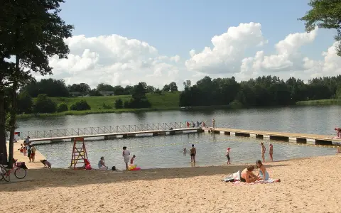 Słoneczne plaże na Mazurach. Ludzie odpoczywają na piasku i w wodzie, ciesząc się letnim dniem.
