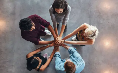 Un gruppo di persone unisce le mani, un'immagine che incarna la social definizione di unità e collaborazione.