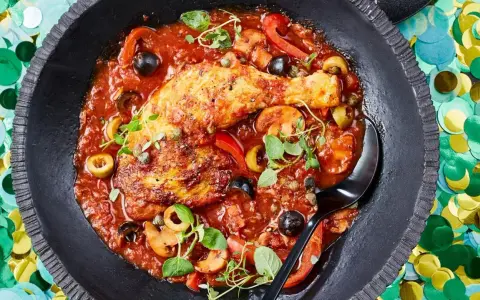 Herzhaftes Pollo Cacciatore in Tomatensauce mit Oliven, Kapern und Pilzen, garniert mit frischen Kräutern.