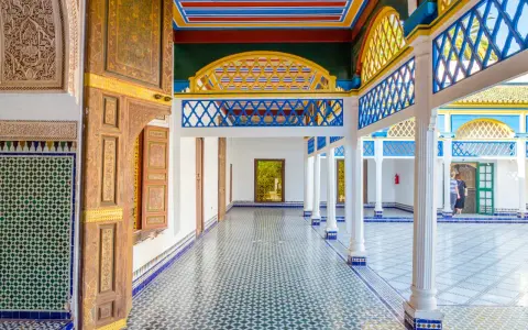 Kolorowy dziedziniec w Maroko, Marrakesz. Wzory geometryczne na ścianach i podłodze, zdobione drzwi i kolorowy sufit.