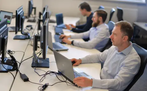 Zespół pracuje nad **static testing**, skupiony na ekranach komputerów w biurze.