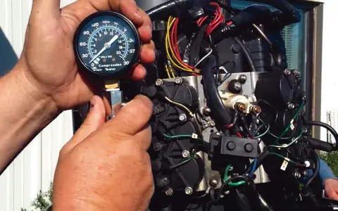Mains d'un mécanicien utilisant un testeur de compression sur un moteur hors-bord. Le moteur se lance mais ne démarre pas essence.