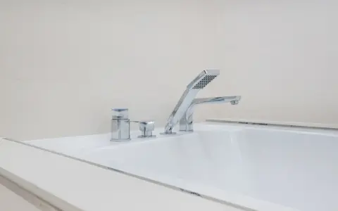 Elegancka bateria wannowa jednootworowa z chromowanymi elementami i słuchawką prysznicową, idealna do nowoczesnej łazienki.