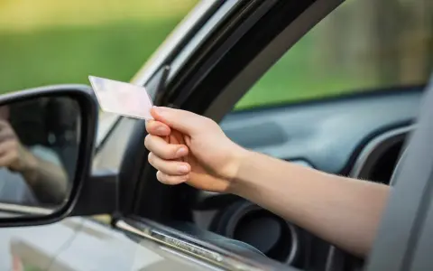 Mano che mostra la patente, in linea con l'articolo 126 bis del codice della strada.