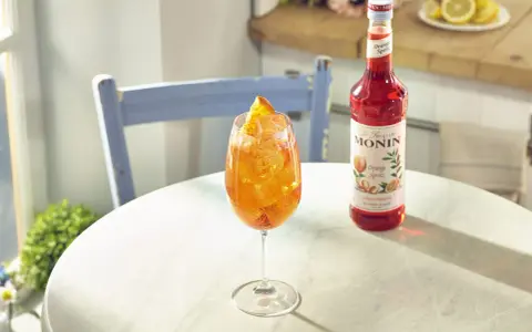 Orzeźwiający drink z syropem Monin Orange Spritz, lodem i pomarańczą. Idealny przepis na letnie popołudnie.