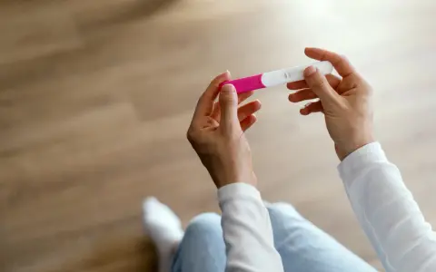 Dłonie trzymające test ciążowy, być może szukając bardzo wczesnych objawów ciąży przed miesiączką.
