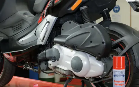 Skuter Gilera z widocznym elementem napędowym. Puszka środka do czyszczenia hamulców obok sugeruje problemy, być może związane z zużytym wariatorem w skuterze objawy.