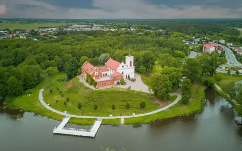 Zamek w Gostyninie, perła pojezierza gostynińsko-włocławskiego, wznosi się nad jeziorem, otoczony zielenią.