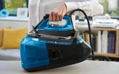 Mano che solleva un ferro da stiro moderno blu e nero, con serbatoio trasparente e tecnologia Silence.