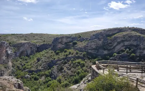 Impresionante vista del **barranco del Río Dulce**, con sus paredes rocosas, vegetación exuberante y un mirador de madera.