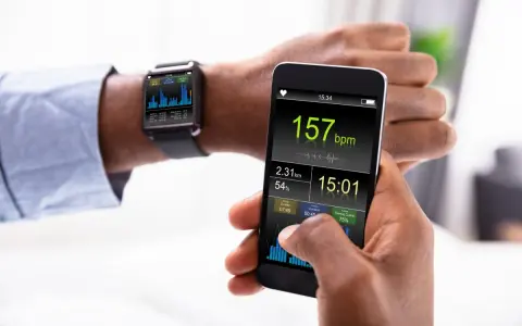 Mężczyzna sprawdza na smartfonie i zegarku dane treningowe: tętno 157 bpm, dystans 2.31 km. Zegarek mierzący ciśnienie pokazuje wykresy.